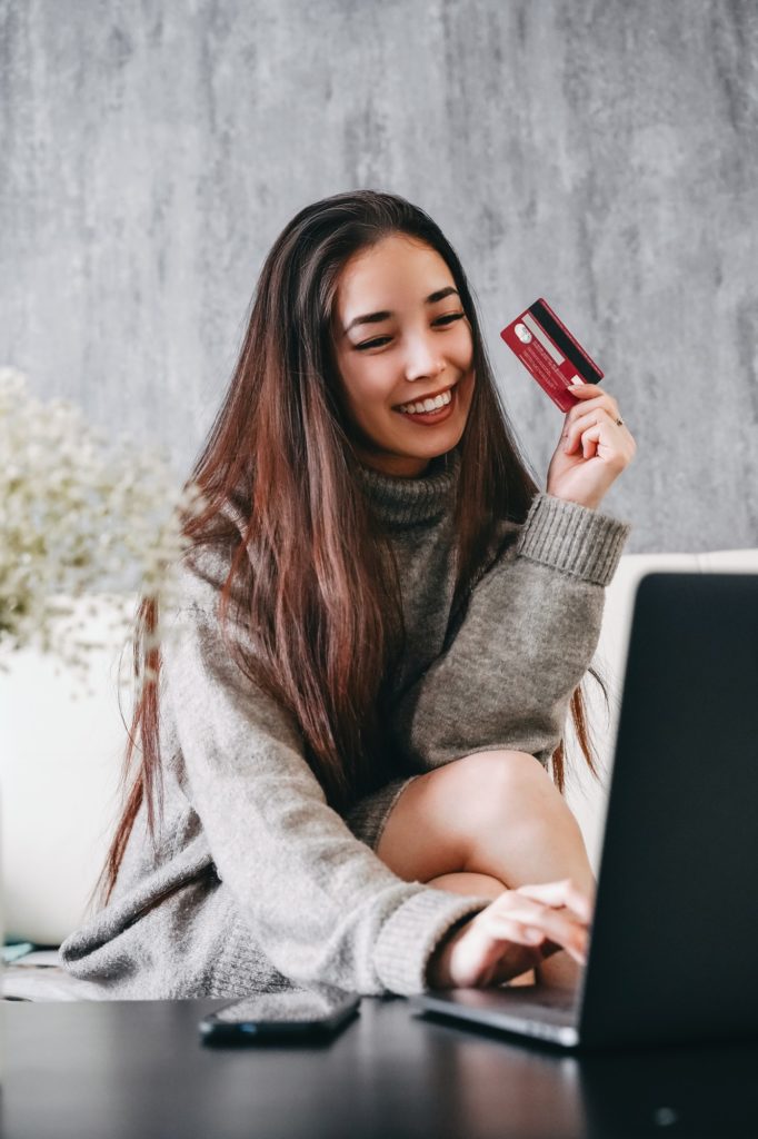 Asian girl makes online purchases over the internet using a laptop and a bank card. Online shopping